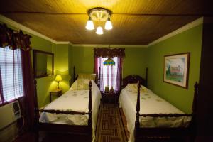 two beds in a room with green walls and windows at Bees B & B in Mount Airy