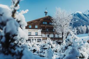 ein schneebedecktes Gebäude mit Bäumen davor in der Unterkunft Batzenhäusl in Seefeld in Tirol
