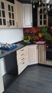una cucina con armadi in legno e un dipinto di frutta di Квартира 3-х комнатная a Temirtaū