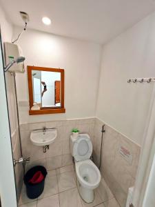 a bathroom with a toilet and a sink and a mirror at Room-Cola Inn in Siquijor