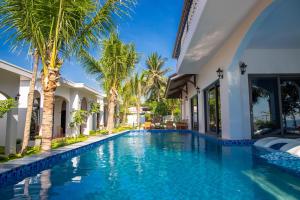 a swimming pool in a villa with palm trees at La'mer Villa Mũi Né in Phan Thiet