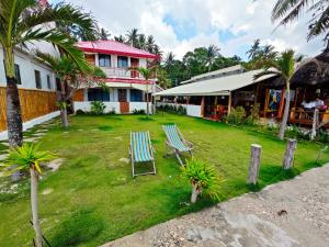 two chairs on a lawn in front of a house at Room-Cola Inn in Siquijor