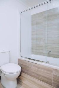 a bathroom with a toilet and a glass shower at Beachside Townhouse in Mornington