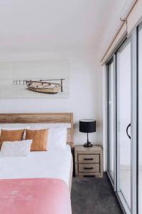a bedroom with a bed and a lamp on a night stand at Beachside Townhouse in Mornington