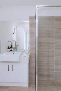 a white bathroom with a shower and a sink at Beachside Townhouse in Mornington