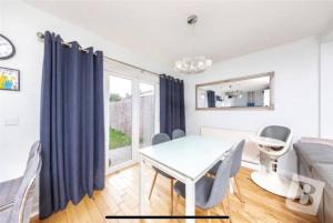 a dining room with a table and chairs and a window at End of Terrace 4 bedroom 2 living room home in London in Harold Wood