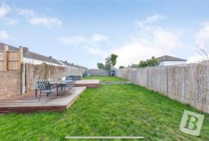 un patio trasero con una terraza de madera y una valla en End of Terrace 4 bedroom 2 living room home in London en Harold Wood