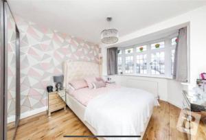 1 dormitorio con cama blanca y almohadas rosas en End of Terrace 4 bedroom 2 living room home in London en Harold Wood