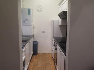 a kitchen with white appliances and a wooden floor at Kent Gardens Apartment in Perivale