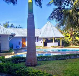 una palmera frente a una casa con piscina en Galu Gardens Diani Beach ,Coastal Apartments by Nest & Nomad en Kwale
