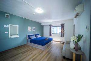 Dormitorio azul con cama y sofá en Baansuay Rattanathibet Apartment en Nonthaburi