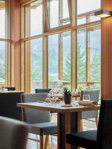 a dining room with a table and chairs and windows at Corona Dolomites Hotel in Andalo