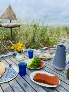 a wooden table with plates of food on it at Harbour Living in Hvide Sande