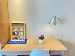una scrivania con una lampada e un vaso di fiori sopra di Summer Suites KLCC By Whollmark a Kuala Lumpur