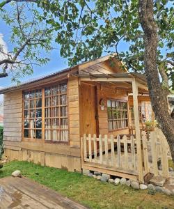 a wooden cabin with a fence in front of a tree at Mơ Garden Retreat DaLat in Da Lat
