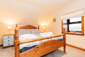 a bedroom with a wooden bed and a window at The Stable at Clauchan Holiday Cottages in Gatehouse of Fleet