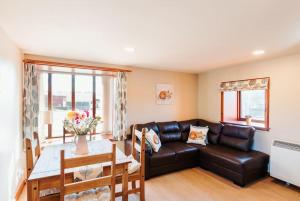 a living room with a leather couch and a table at The Stable at Clauchan Holiday Cottages in Gatehouse of Fleet
