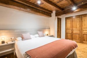 a bedroom with a large white bed and wooden ceilings at Riu Nere - Pleta de Jus by Totiaran in Naut Aran