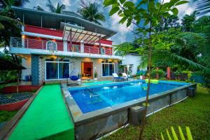 a villa with a swimming pool in front of a house at Spicy Mango Villa Elegano - Luxurious Villa Near Nagaon Beach, Alibag in Nagaon