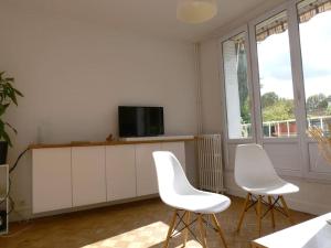 uma sala de estar com duas cadeiras brancas e uma televisão em Appartement de designer, Cosy Lumineux, 3 chambres em Le Kremlin-Bicêtre