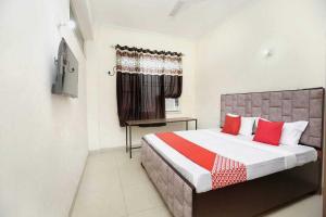um quarto com uma cama grande e almofadas vermelhas em OYO Hotel Golden Crown em Sirhind