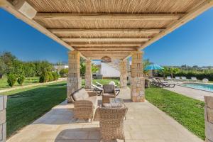 un patio con pergolato in legno e piscina di La Serrazza by BarbarHouse a Marina di Pescoluse