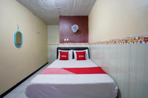 a bedroom with a large bed with red pillows at OYO 927 Carina Hotel in Mojokerto