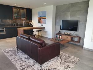 sala de estar con sofá de cuero marrón y TV en Endless Views en Ciudad del Cabo