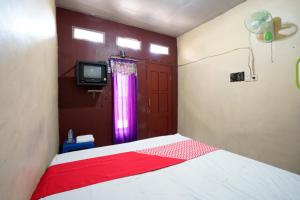 a bedroom with a bed with a red and white blanket at OYO 927 Carina Hotel in Mojokerto
