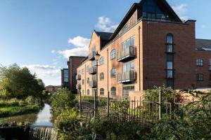 un edificio de ladrillo con un río delante de él en Cotels - The Millhouse NEWLY REFURBISHED MODERN APARTMENTS WITH ULTRAFAST BROADBAND, FREE PARKING & A WORK DESK en Derby