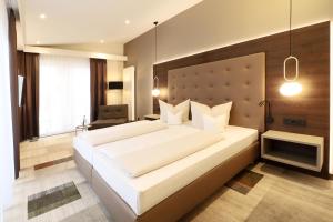 a bedroom with a large white bed and a chair at Hotel Goldene Rose in Heidelberg