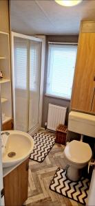 a bathroom with a sink and a toilet at Herons Mead Touring Park and Fishing Lakes - Plot 18 in Orby