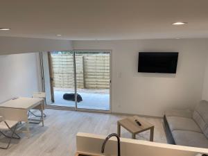 a living room with a couch and a tv on a wall at Joli logement au pied des Alpilles in Eyguières