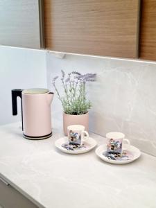 dwie filiżanki kawy na blacie kuchennym z garnkiem w obiekcie Apartment in Tapiola w mieście Espoo