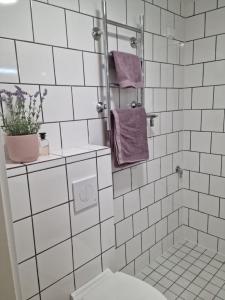 W wyłożonej białymi kafelkami łazience znajduje się toaleta i fioletowe ręczniki. w obiekcie Apartment in Tapiola w mieście Espoo
