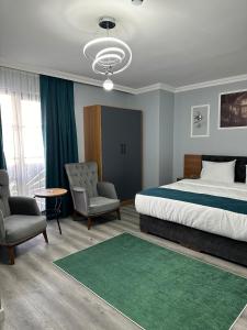 1 dormitorio con cama, sillas y alfombra verde en Asgard Hotel, en Beylikduzu