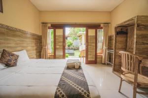 a bedroom with a large white bed and a chair at Pondok Lulik Homestay Canggu in Canggu