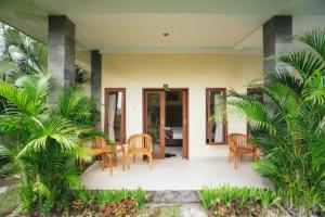 a porch of a house with chairs and a table at Pondok Lulik Homestay Canggu in Canggu