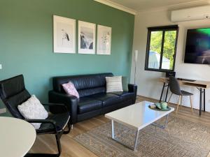 un salon avec un canapé en cuir noir et une table dans l'établissement Serenity Cottage Wonthaggi, à North Wonthaggi