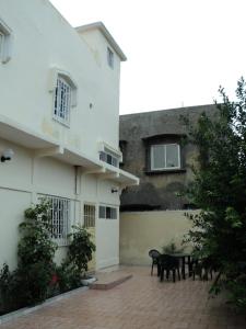 a patio with a table and chairs in front of a building at Fayes Apartments in Brusubi