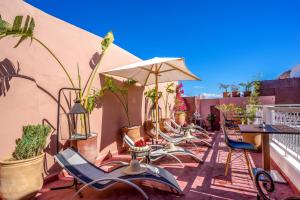 um pátio com cadeiras e mesas e um guarda-sol em Riad Al Madina Marrakech & Spa em Marrakech