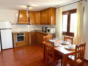 cocina con mesa con sillas y nevera blanca en Casa Los Kikos By Solymar Holiday, en Alcaucín