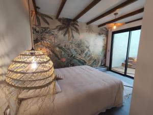 1 dormitorio con 1 cama con una pintura en la pared en L'ApparT, meublé de tourisme 4 étoiles, piscine chauffée et vue mer imprenable, en Les Avirons