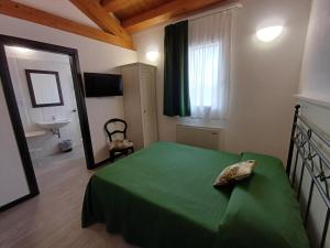una camera con letto verde, specchio e lavandino di Arneroni a Codognè