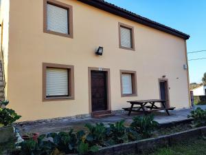 une maison avec une table de pique-nique devant elle dans l'établissement Apartamentos La Portilla de El Tejo, à El Tejo