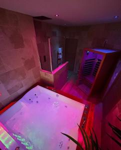 bañera de hidromasaje grande en una habitación con luces moradas en Bella Notte Spa en Dijon