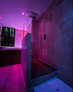 baño con iluminación púrpura y ducha a ras de suelo en Bella Notte Spa en Dijon