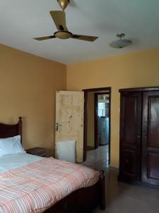 a bedroom with a bed and a ceiling fan at Fayes Apartments in Brusubi