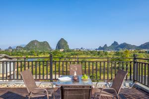 une table et des chaises sur une terrasse avec des montagnes en arrière-plan dans l'établissement Guilin Village Creek Inn, à Guilin