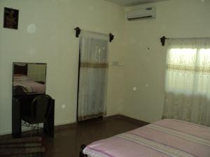 a bedroom with a bed and a mirror and a window at Fayes Apartments in Brusubi